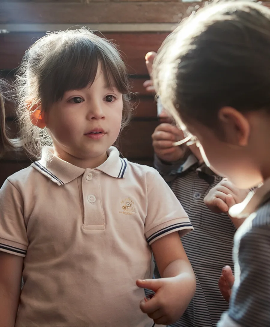 A child gazing thoughtfully across the room in warm classroom light
